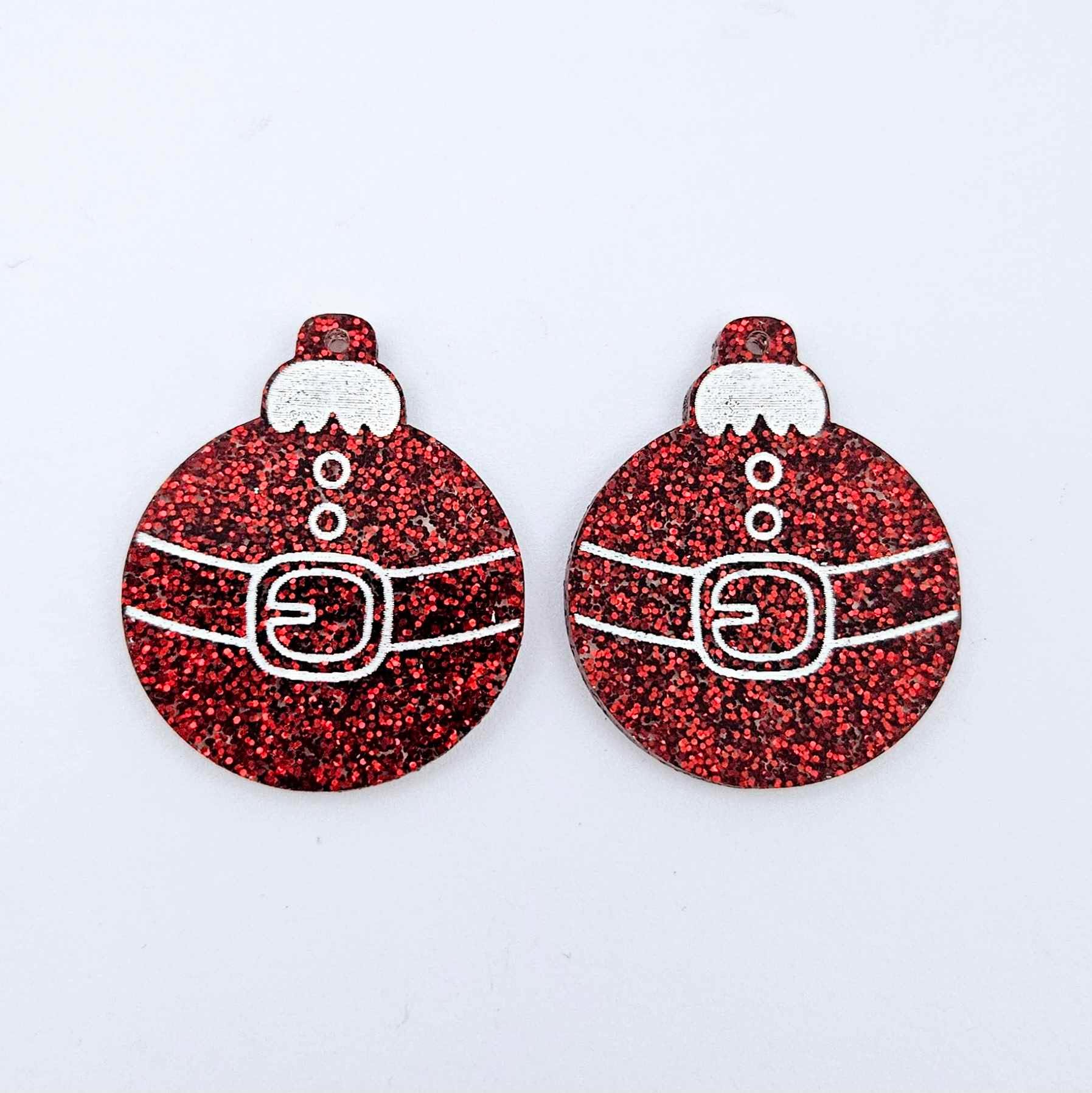 One pair of red glitter Santa bauble dangle blanks with engraved Santa belt and button details paint filled white, shown laying flat