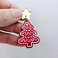 One deep red marble cookie Christmas tree dangle with engraved icing details paint filled in light pink and white, assembled with a 16mm gold mirror star topper