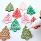 Cookie Christmas tree dangle earring blanks in solid red, solid green and pastel pink, showing a mix of paint-filled and unpainted pieces with a Posca paint pen positioned ready to paint fill the engraved details