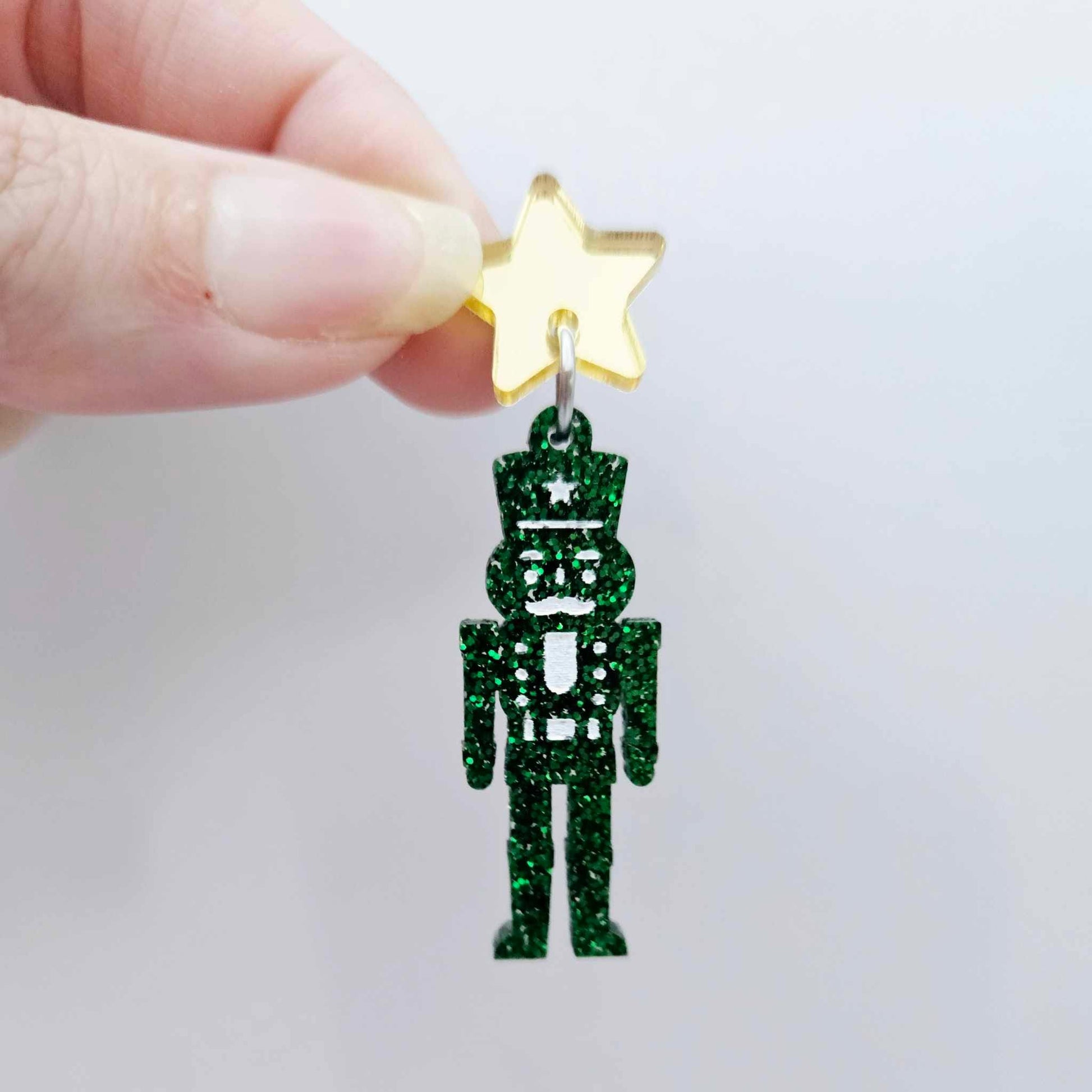 Assembled 40mm nutcracker Christmas dangle earrings in green glitter acrylic with engraved detail paint filled white