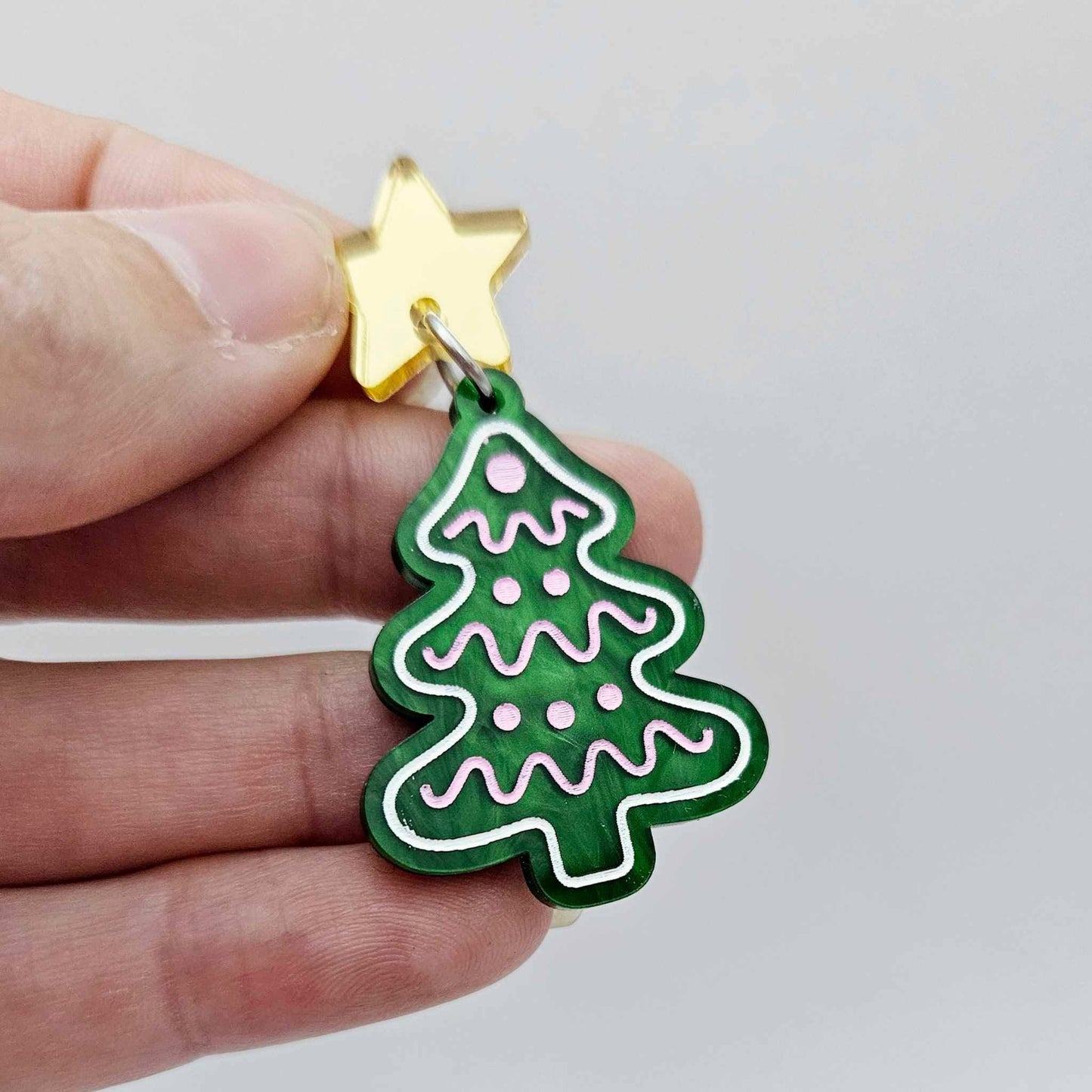 One green marble cookie Christmas tree dangle with engraved icing details paint filled in light pink and white, assembled with a 16mm gold mirror star topper