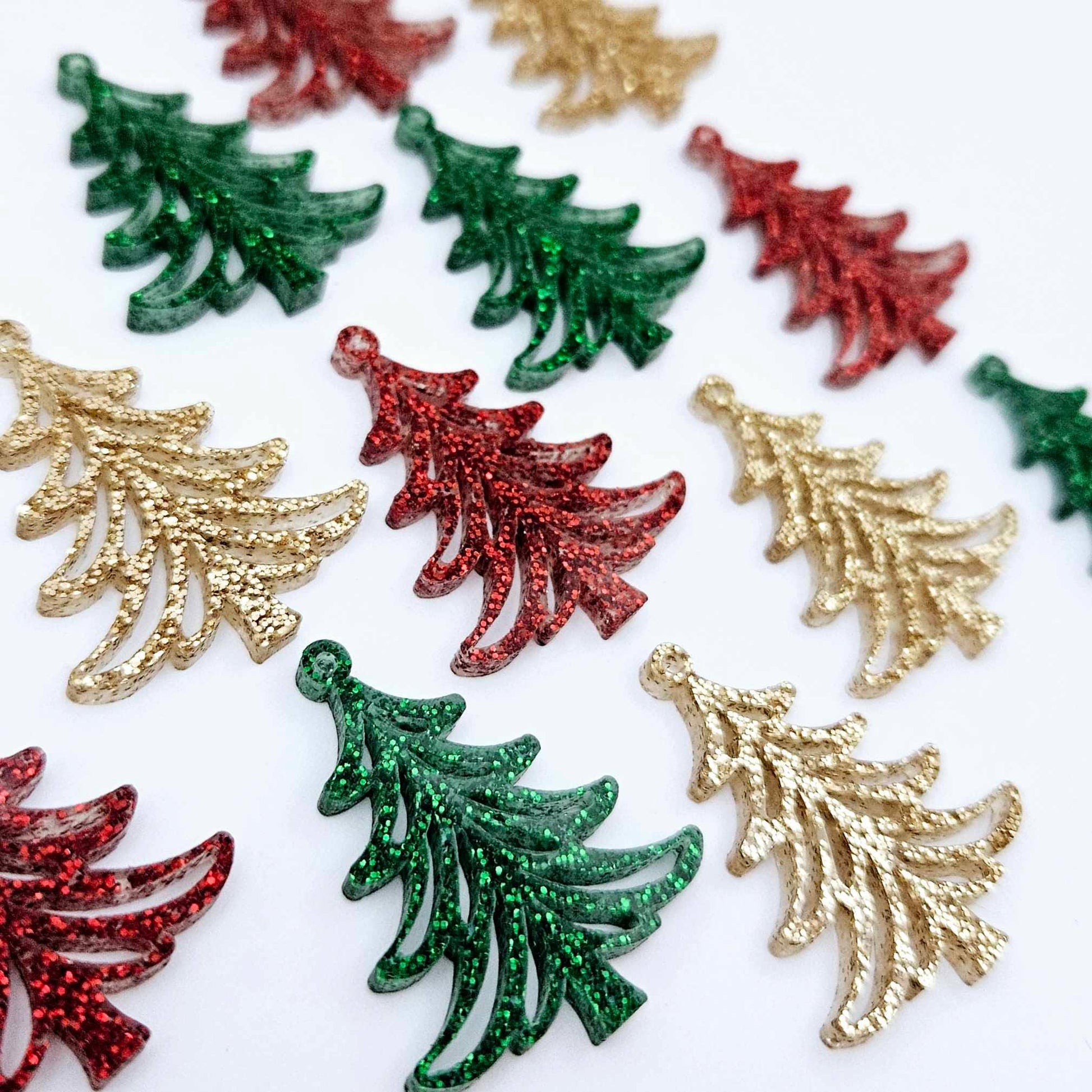 A mixture of green glitter, red glitter and rose gold glitter 35mm Cascade Christmas Tree dangle earring blanks laying flat on a white background.