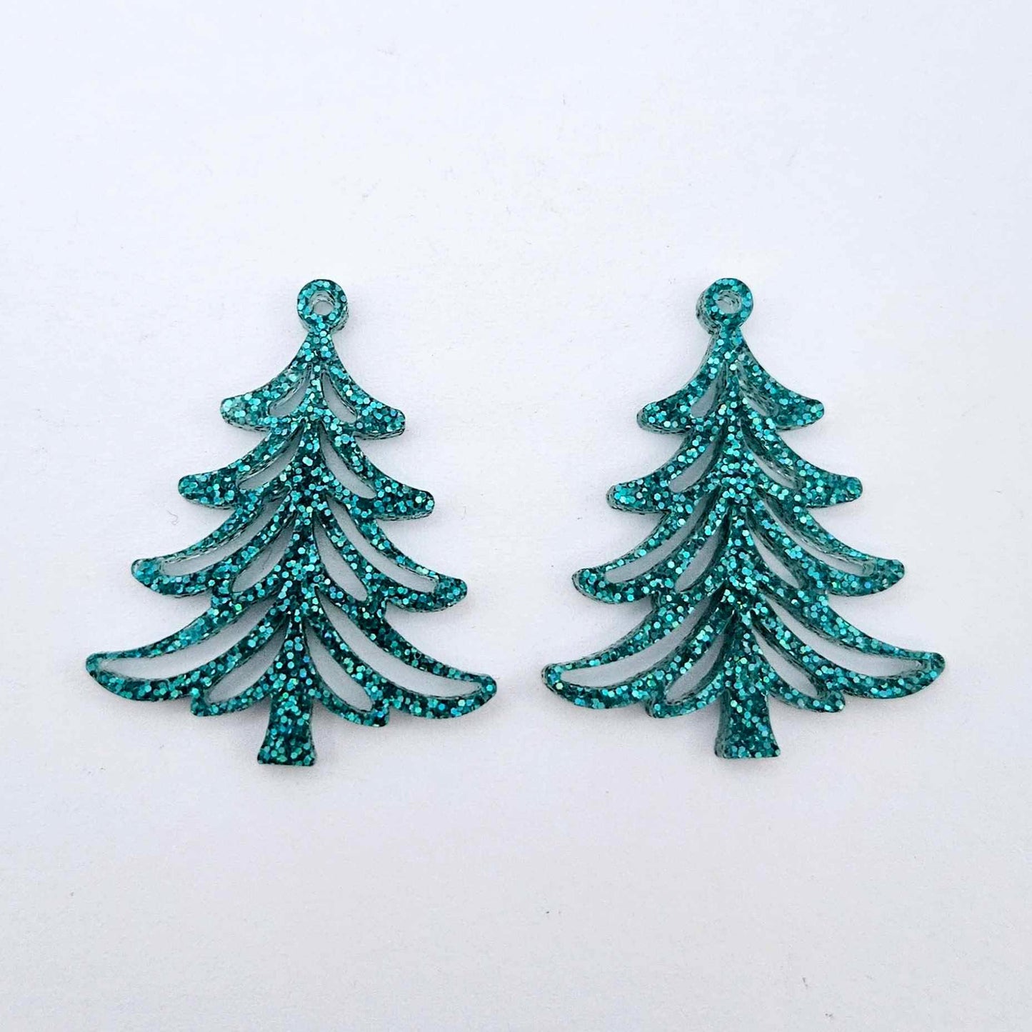 One pair of 35mm teal glitter acrylic Cascade Christmas Tree dangle blanks laying flat on a white background