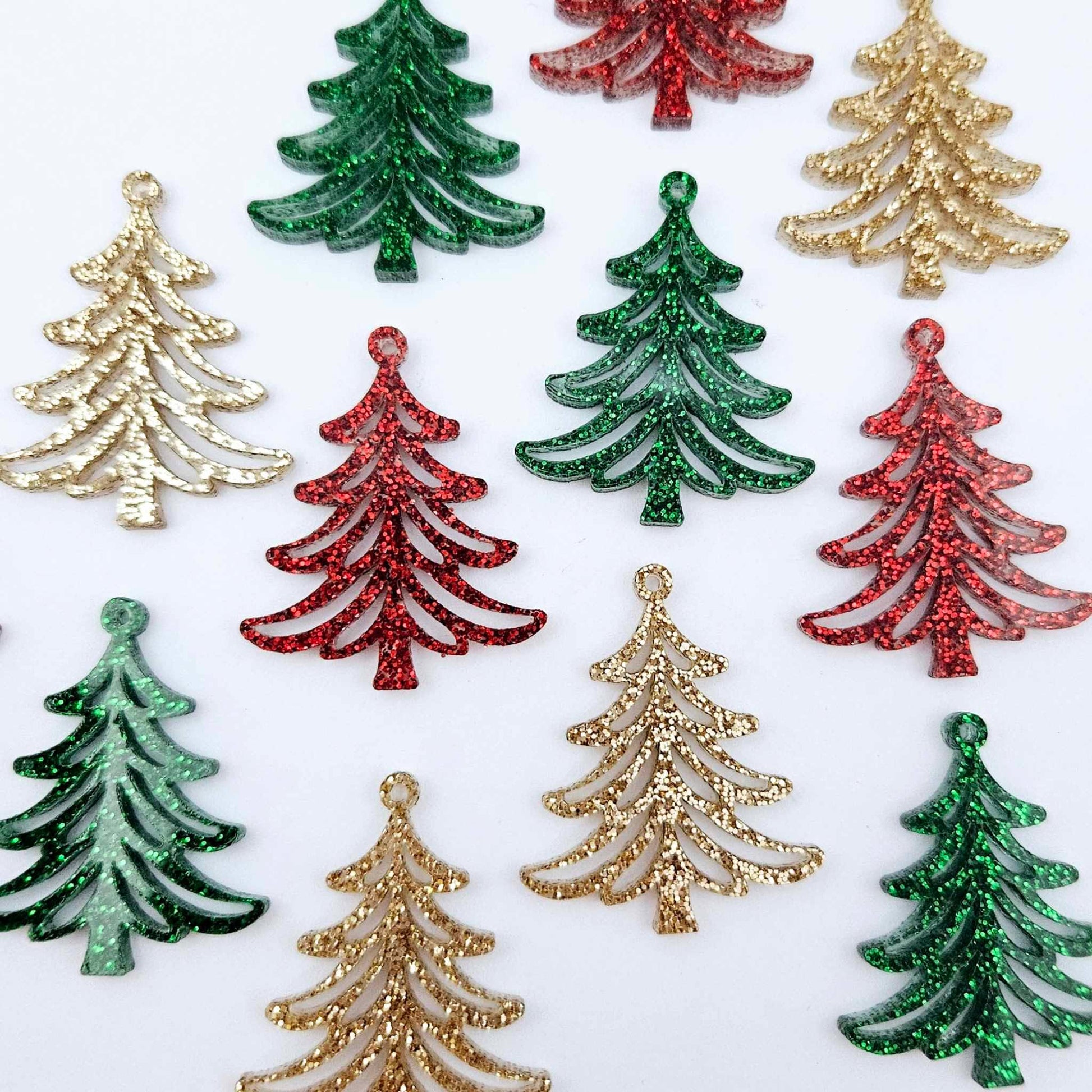 A mixture of green glitter, red glitter and rose gold glitter 35mm Cascade Christmas Tree dangle earring blanks laying flat on a white background.