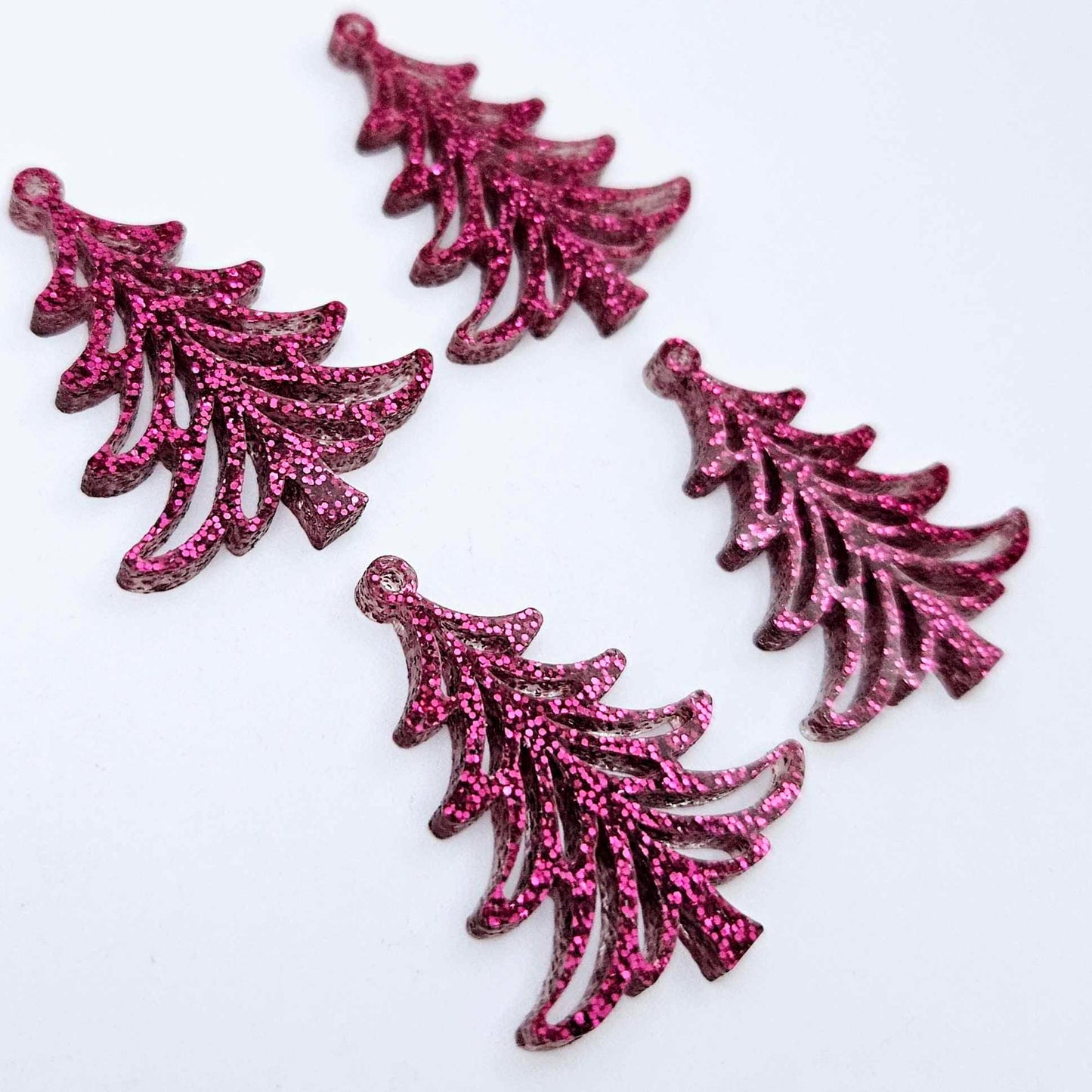 Two pairs of 35mm hot pink glitter Cascade Christmas Tree dangle blanks laying flat on a white background