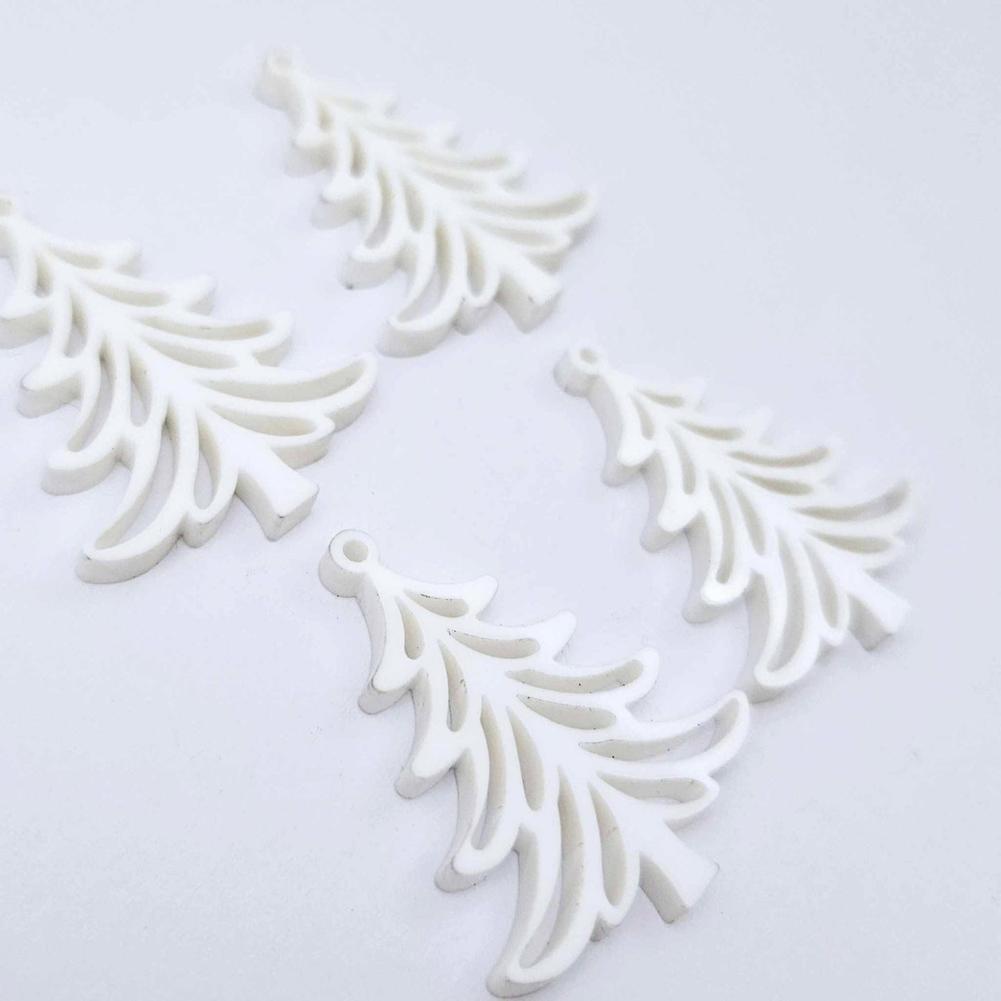 Two pairs of 35mm white acrylic Cascade Christmas Tree dangle blanks laying flat on a white background