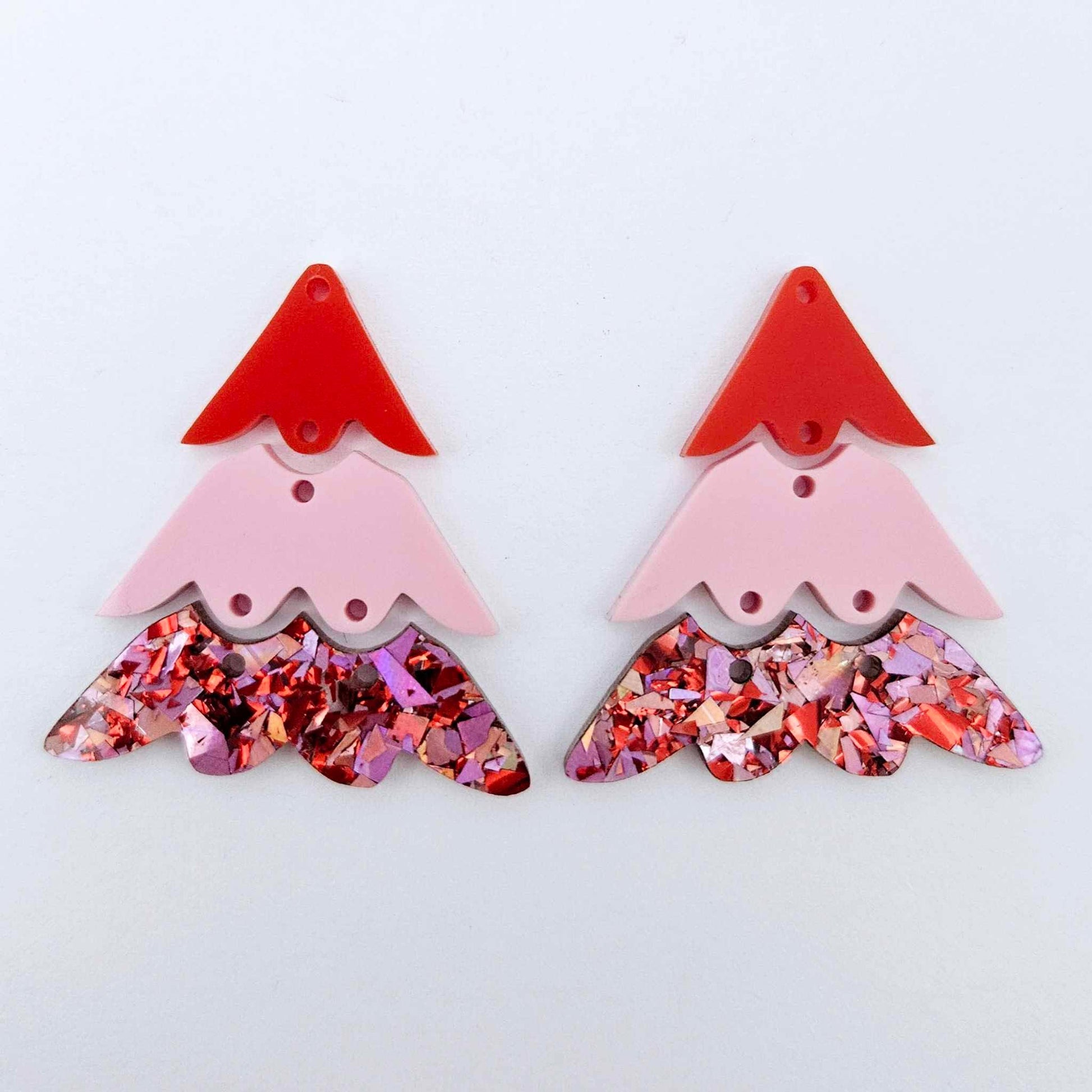 One pair of 40mm three piece Christmas Tree dangle earring blanks in Chunky Love Glitter, Pastel Pink and Solid Red acrylic laying flat on a white background