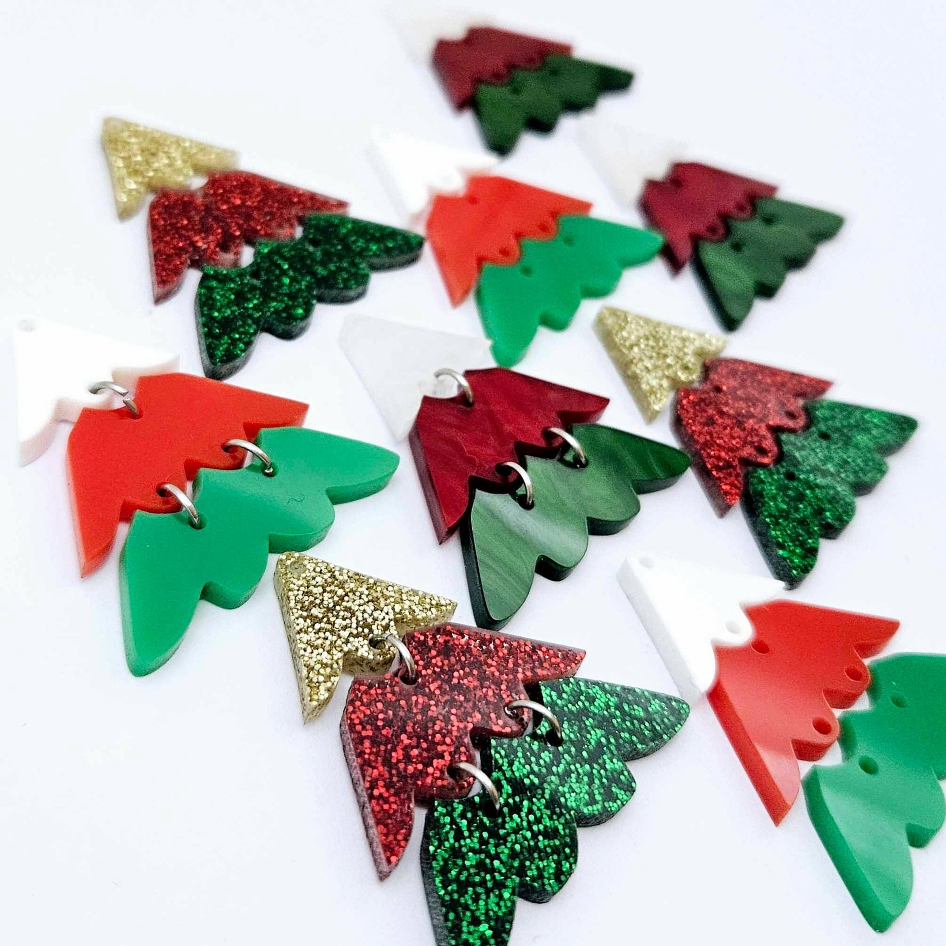 A mixture of the three traditional 40mm three piece Christmas Tree dangle blank designs laying flat on a white background