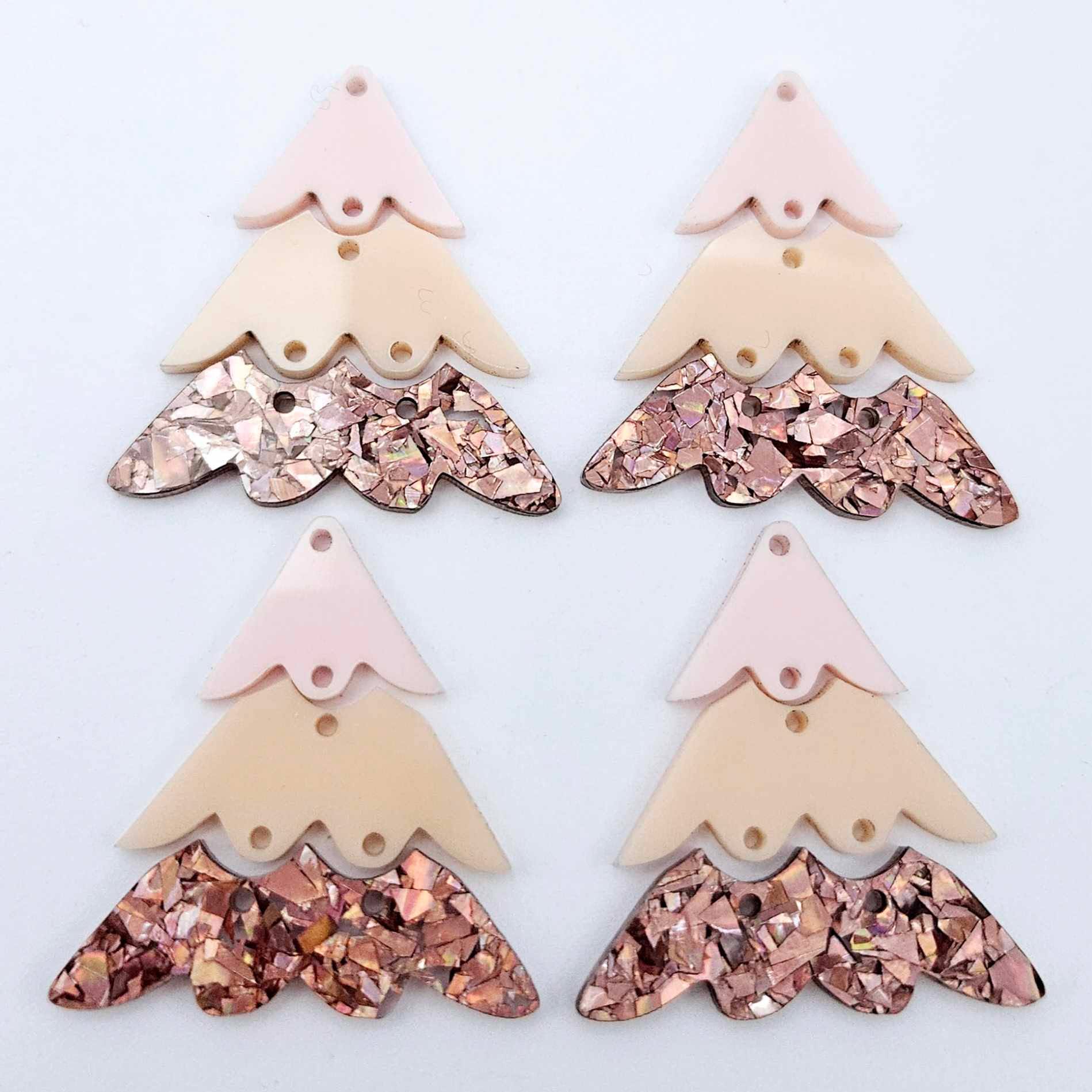 Two pairs of 40mm three piece Christmas Tree dangle earring blanks in chunky holographic rose gold glitter, peach and strawberry milkshake acrylic laying flat on a white background