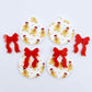 Two pairs of Gingerbread Party UV printed bauble dangle blanks with included red bows laying flat