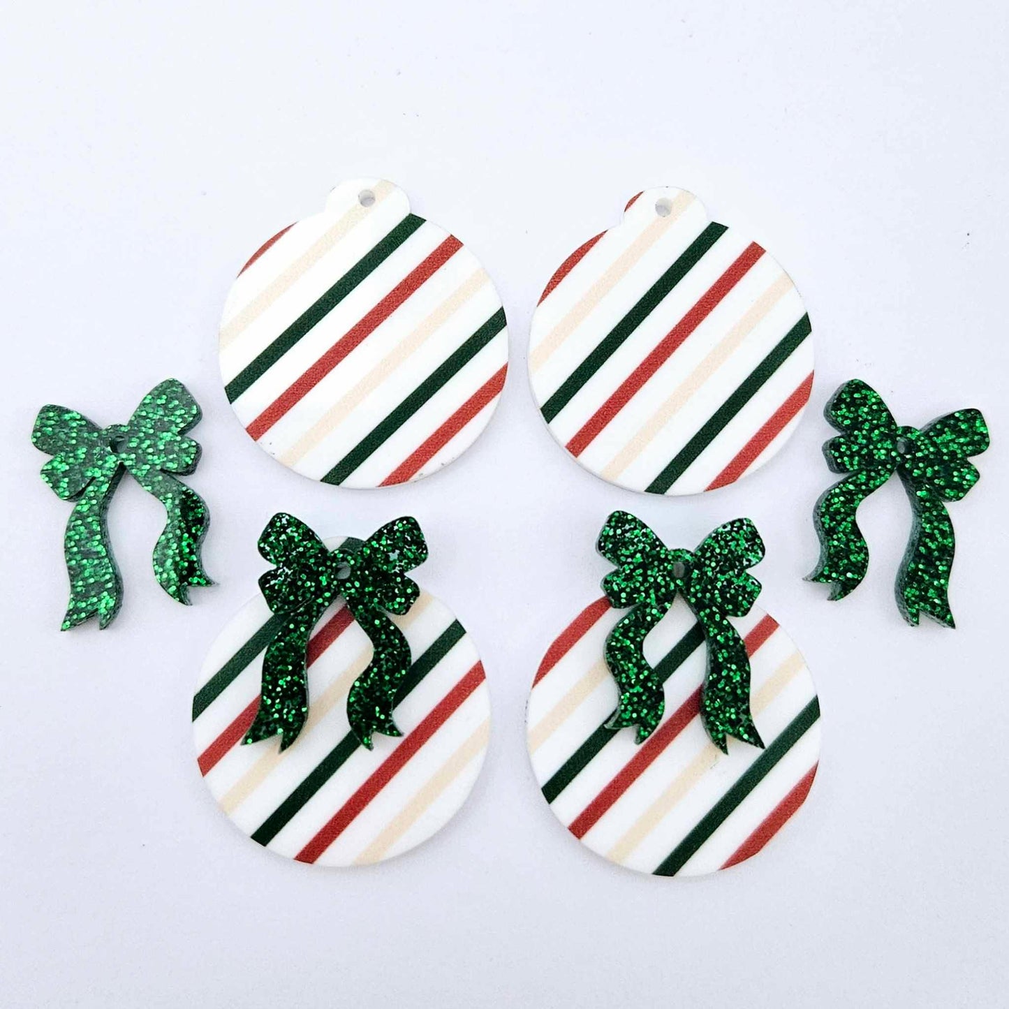 Two pairs of Stripey Christmas UV printed bauble dangle blanks with included green glitter bows laying flat