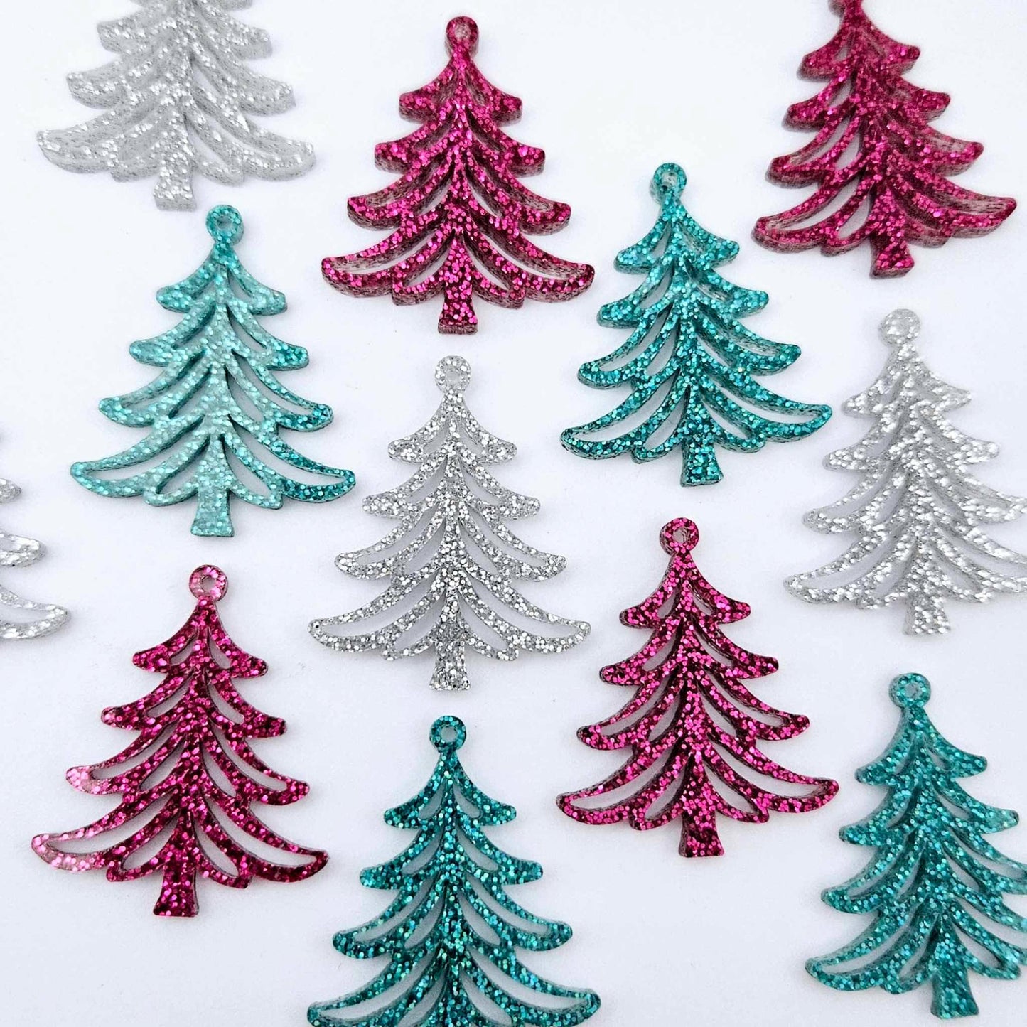 A mixture of hot pink glitter, teal glitter and silver glitter 35mm Cascade Christmas Tree dangle earring blanks laying flat on a white background