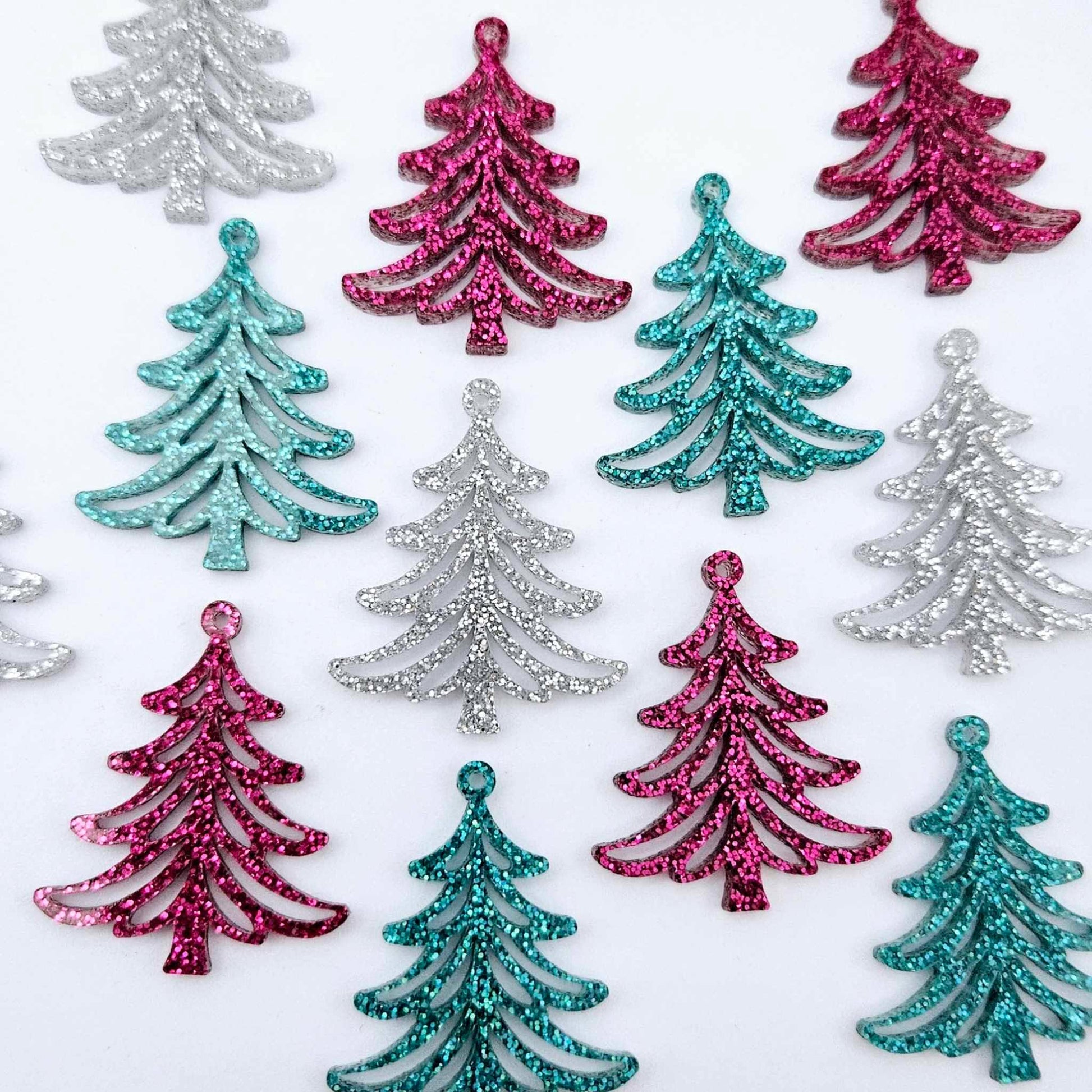 A mixture of hot pink glitter, teal glitter and silver glitter 35mm Cascade Christmas Tree dangle earring blanks laying flat on a white background