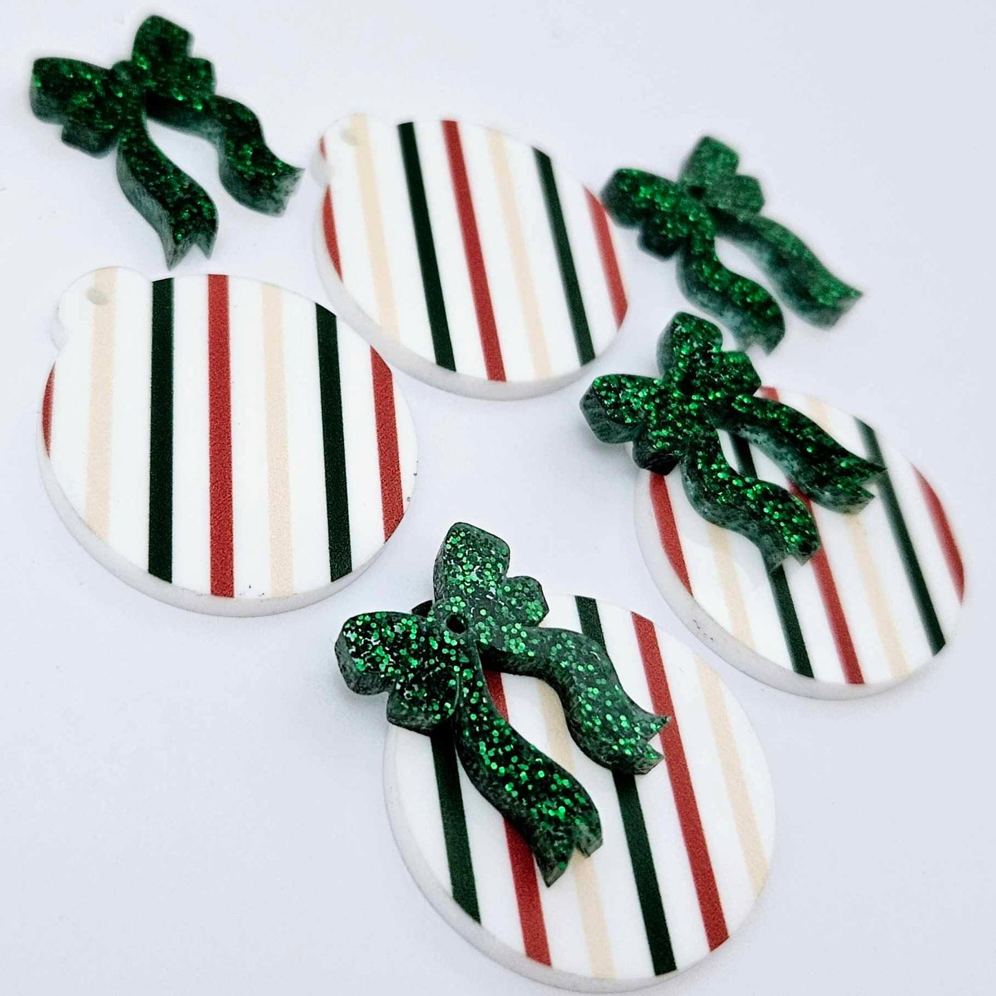 Two pairs of Stripey Christmas UV printed bauble dangle blanks with included green glitter bows laying flat