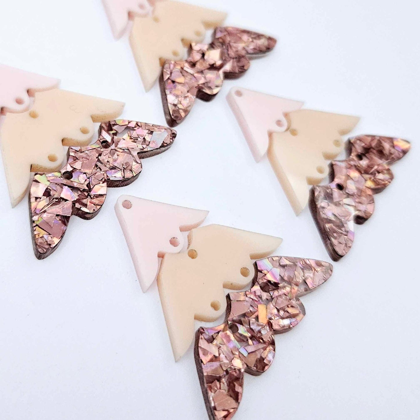 Two pairs of 40mm three piece Christmas Tree dangle earring blanks in chunky holographic rose gold glitter, peach and strawberry milkshake acrylic laying flat on a white background
