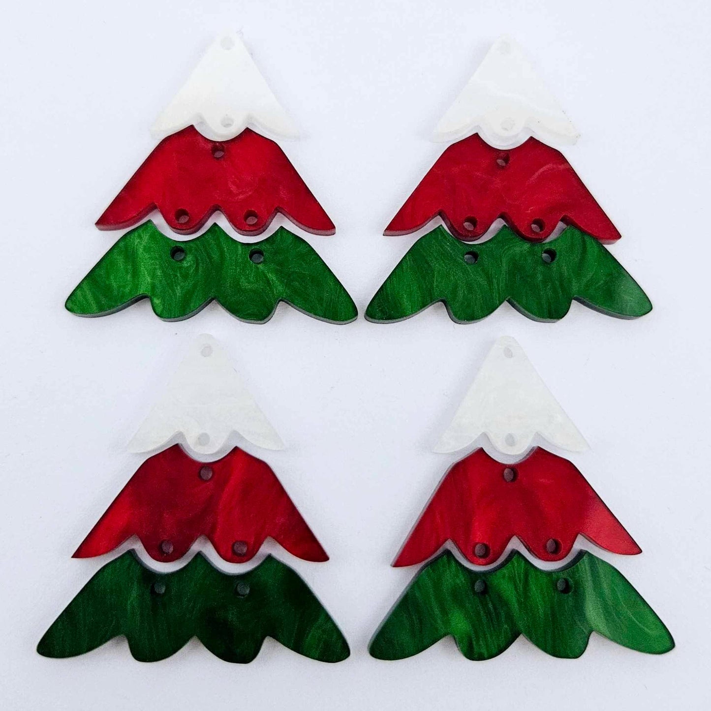Two pairs of 40mm three piece Christmas Tree dangle earring blanks in green marble, red marble and white marble acrylic laying flat on a white background