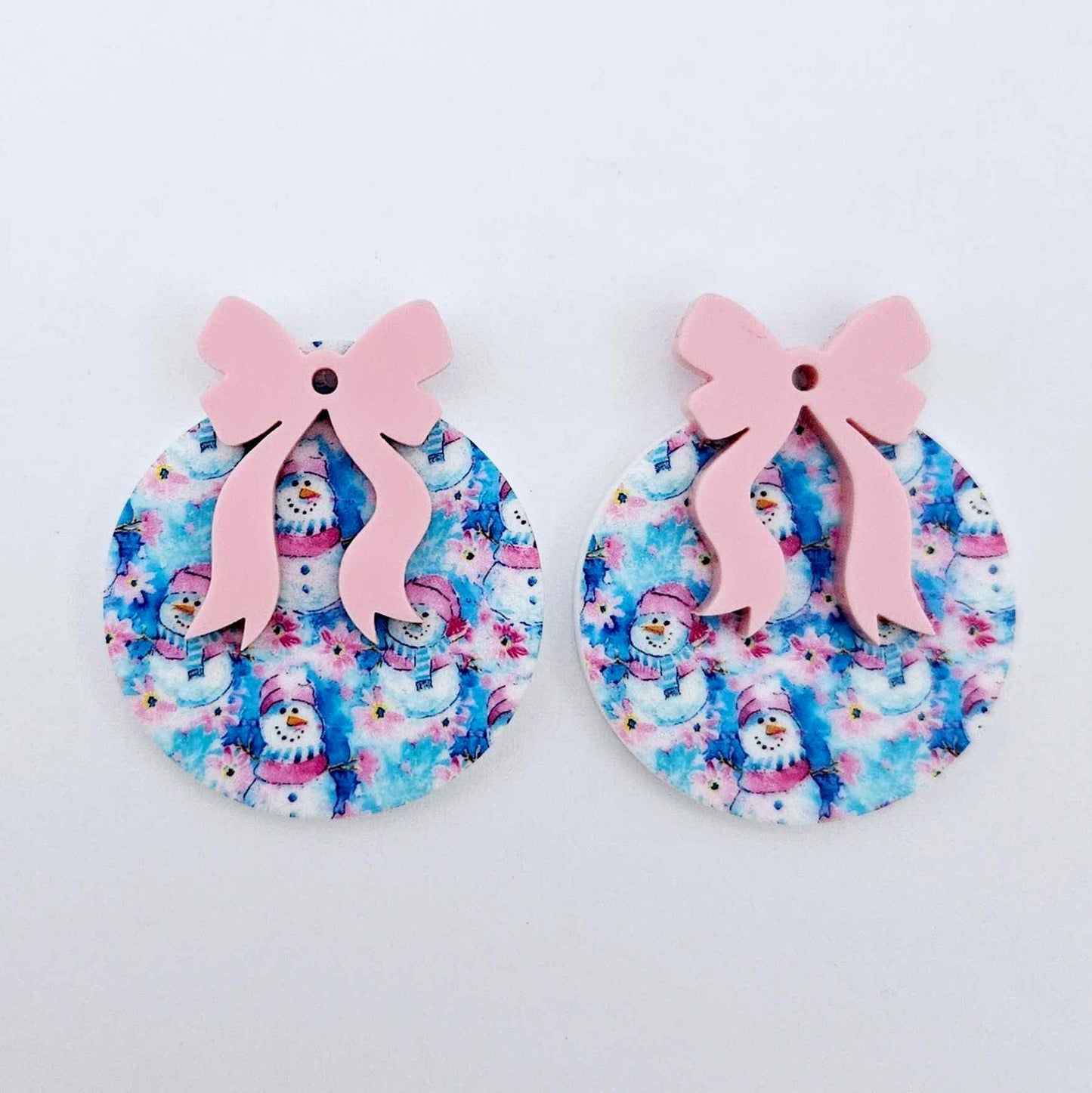 One pair of Snowman Wonderland UV printed bauble dangle blanks with included pastel pink bows laying flat