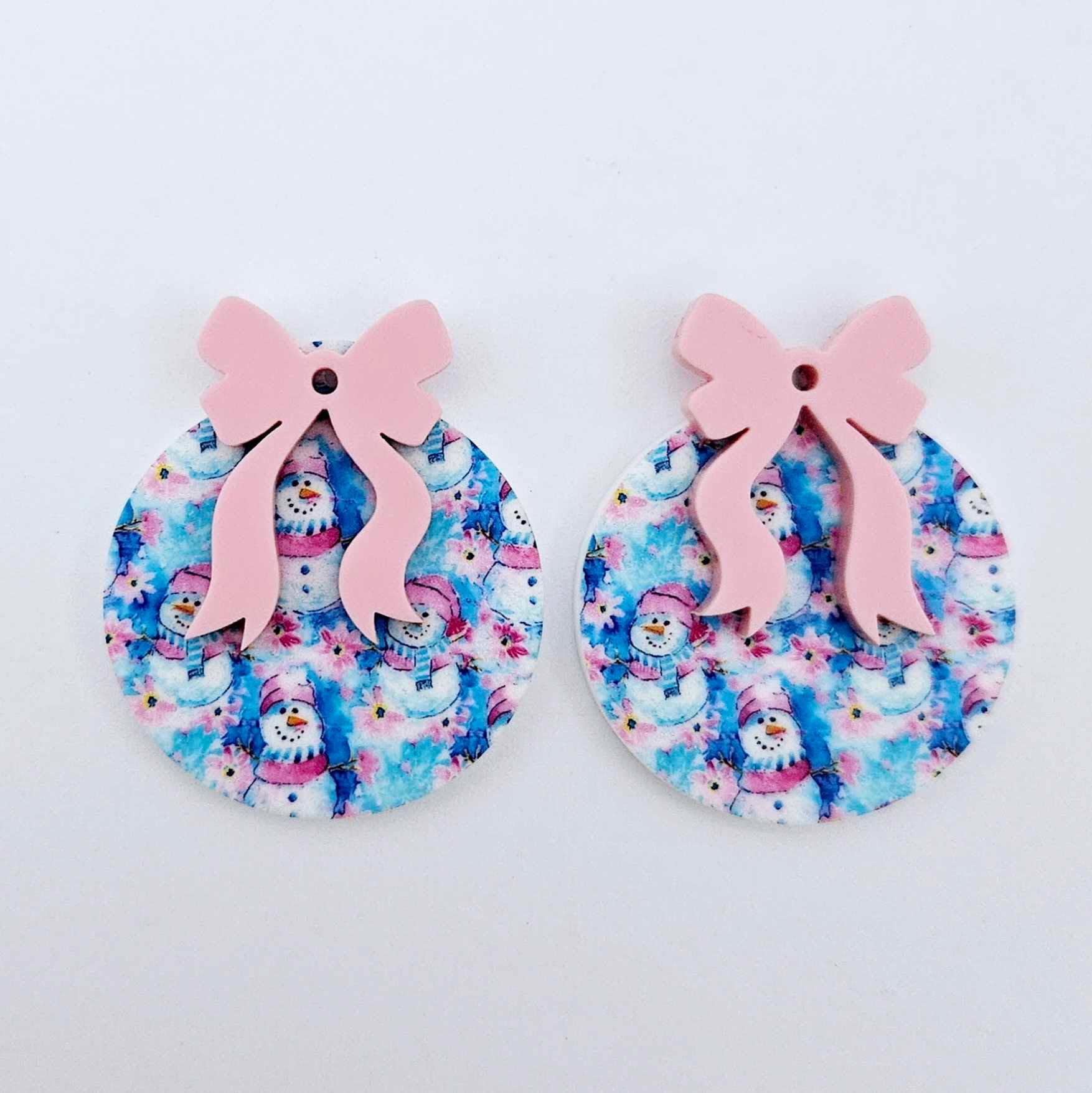 One pair of Snowman Wonderland UV printed bauble dangle blanks with included pastel pink bows laying flat