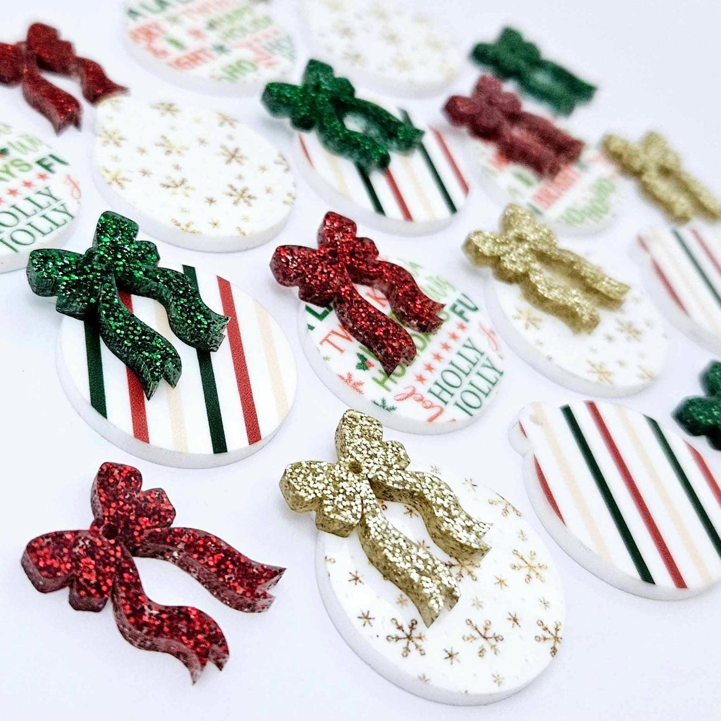 A selection of the three Traditional Christmas UV printed bauble dangle blank designs with their coordinating glitter bows laying flat