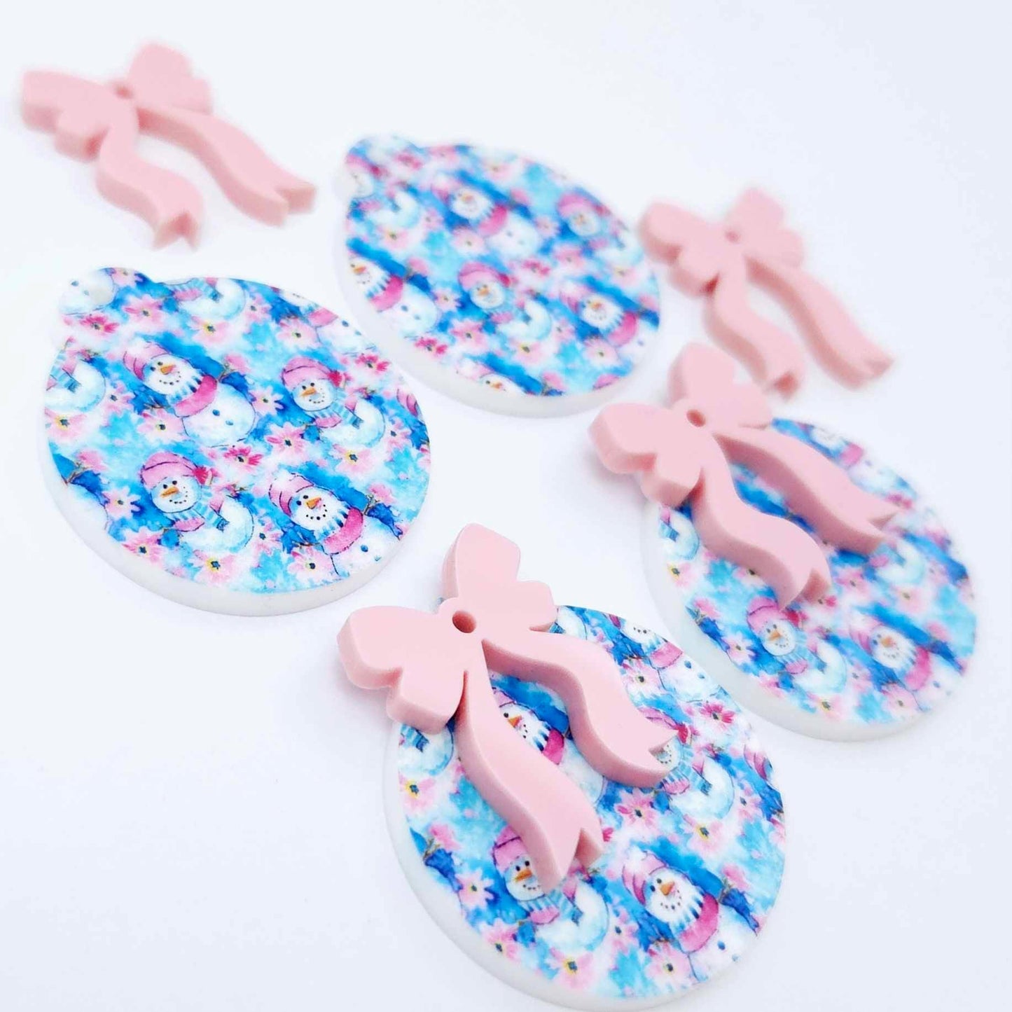 Two pairs of Snowman Wonderland UV printed bauble dangle blanks with included pastel pink bows laying flat