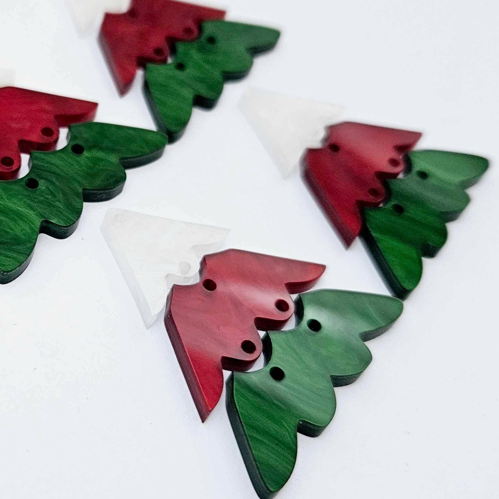 Two pairs of 40mm three piece Christmas Tree dangle earring blanks in green marble, red marble and white marble acrylic laying flat on a white background