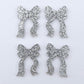 Two pairs of silver glitter acrylic bow dangle earring blanks laying flat