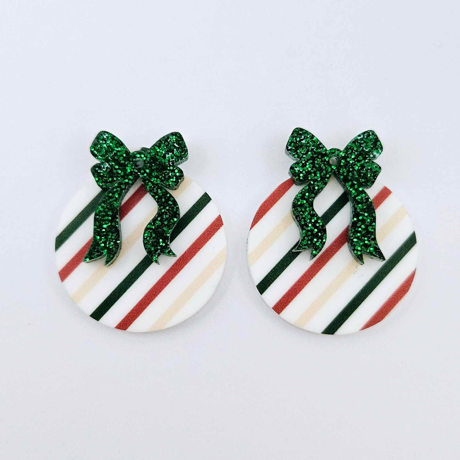 One pair of Stripey Christmas UV printed bauble dangle blanks with included green glitter bows laying flat