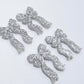 Two pairs of silver glitter acrylic bow dangle earring blanks laying flat