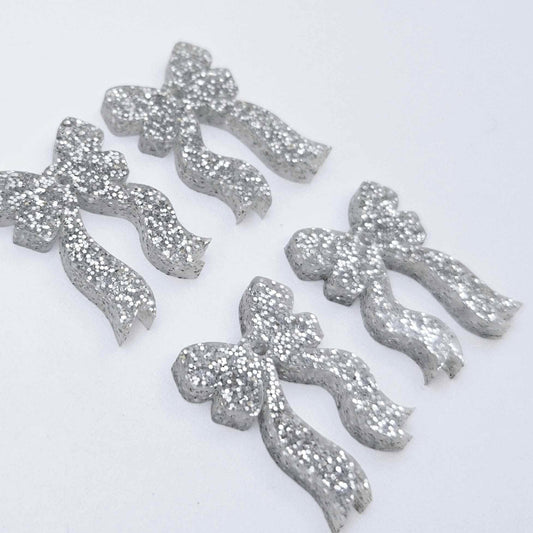 Two pairs of silver glitter acrylic bow dangle earring blanks laying flat