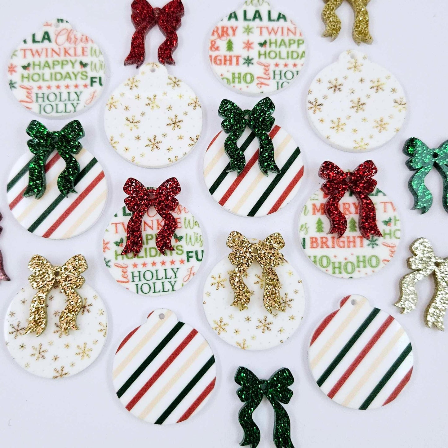 A selection of the three Traditional Christmas UV printed bauble dangle blank designs with their coordinating glitter bows laying flat