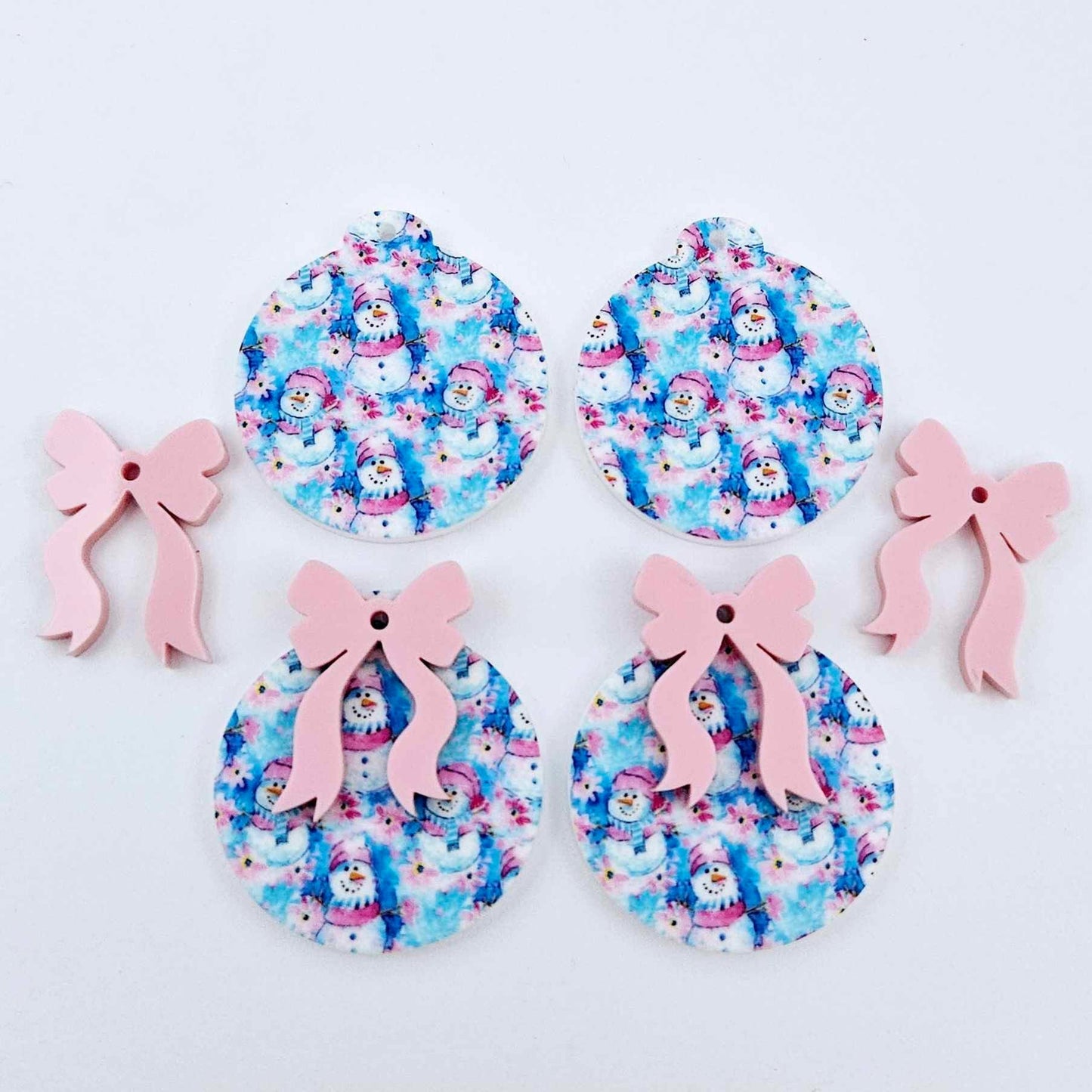 Two pairs of Snowman Wonderland UV printed bauble dangle blanks with included pastel pink bows laying flat