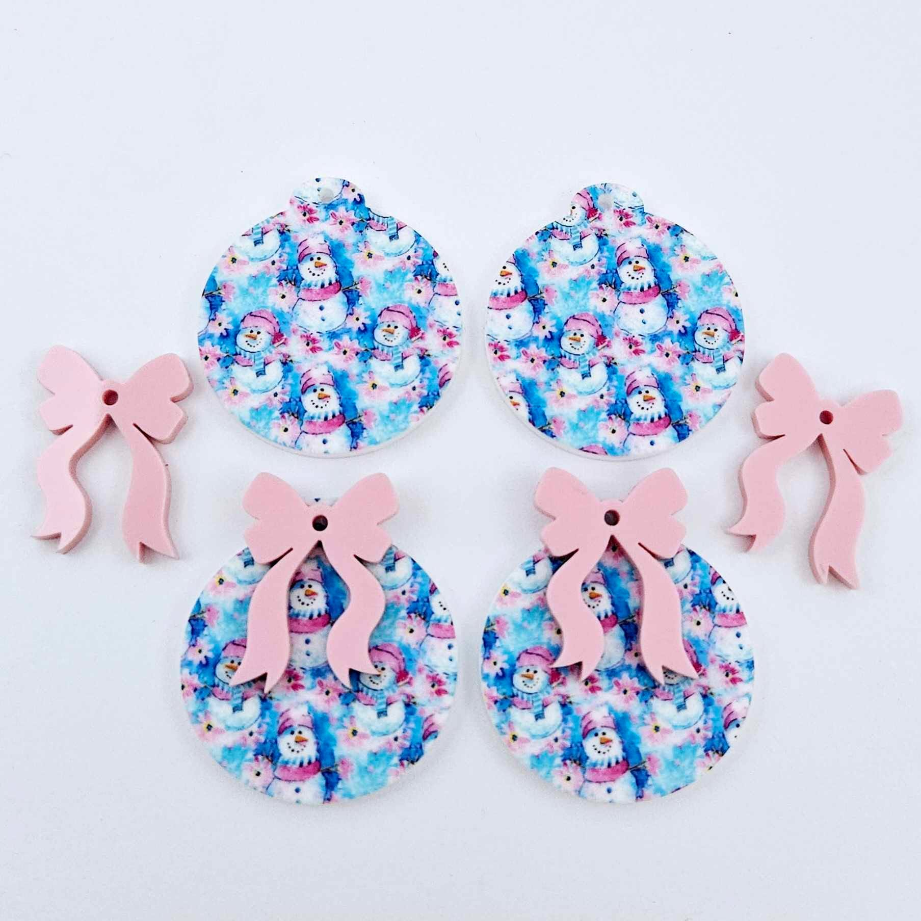Two pairs of Snowman Wonderland UV printed bauble dangle blanks with included pastel pink bows laying flat