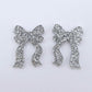 One pair of silver glitter acrylic bow dangle earring blanks laying flat