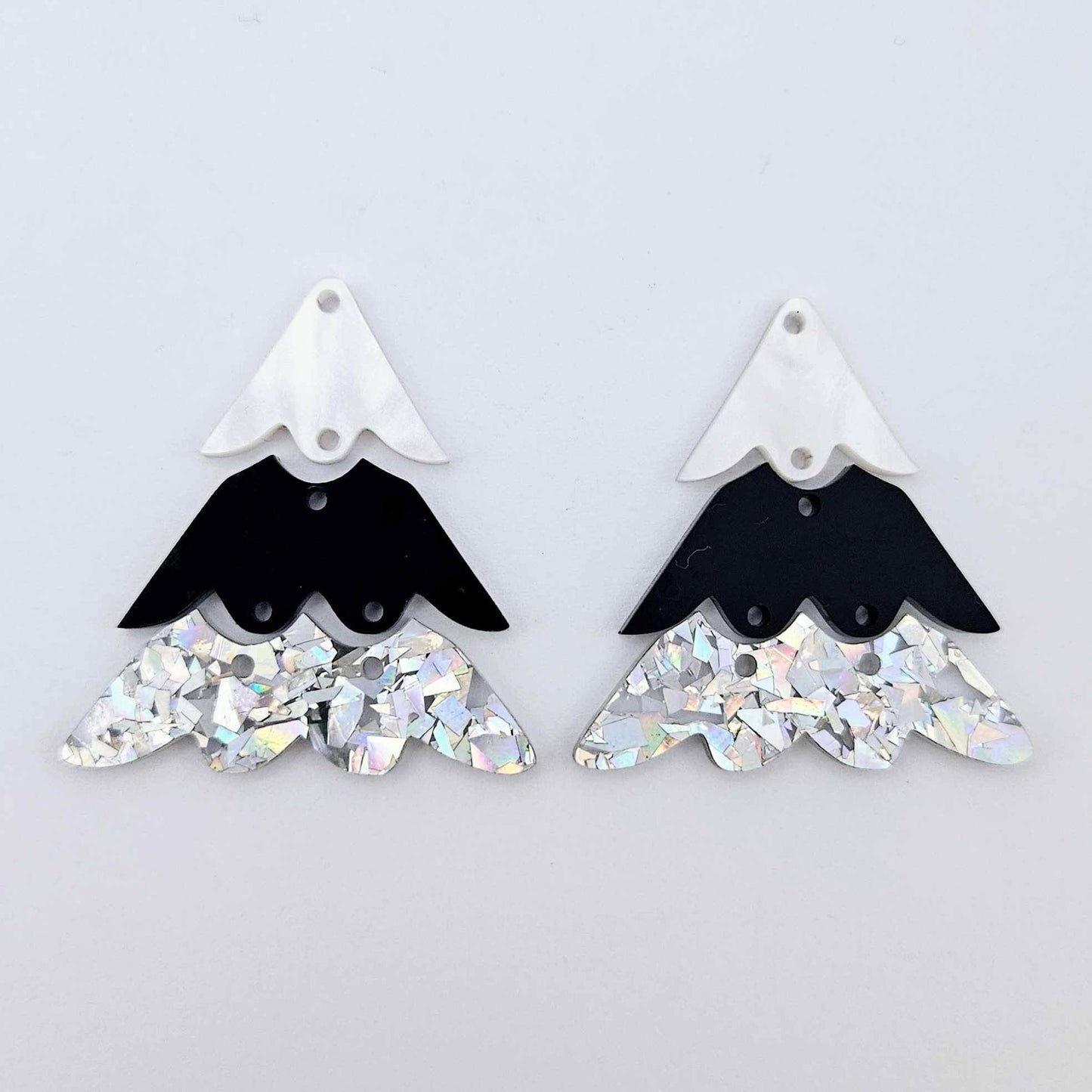 One pair of 40mm three piece Christmas Tree dangle earring blanks in holographic silver glitter, black and white marble acrylic laying flat on a white background