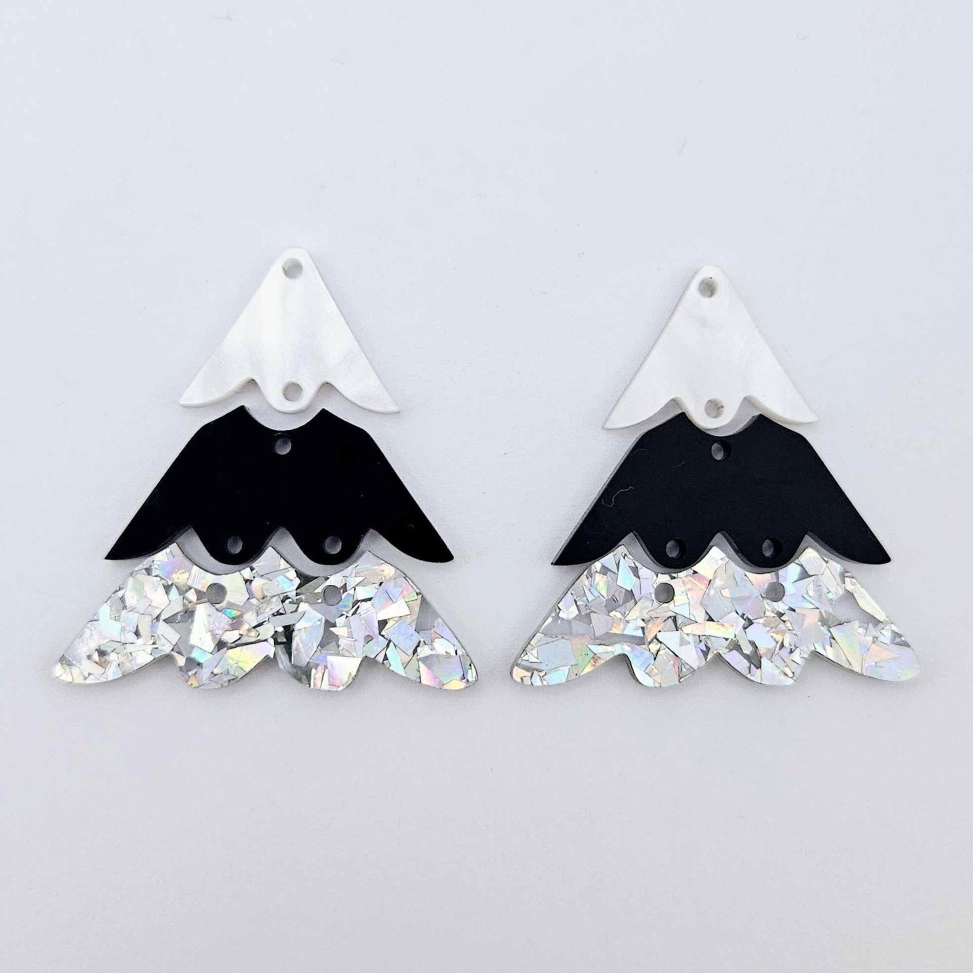 One pair of 40mm three piece Christmas Tree dangle earring blanks in holographic silver glitter, black and white marble acrylic laying flat on a white background