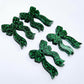 Two pairs of green glitter acrylic bow dangle earring blanks laying flat