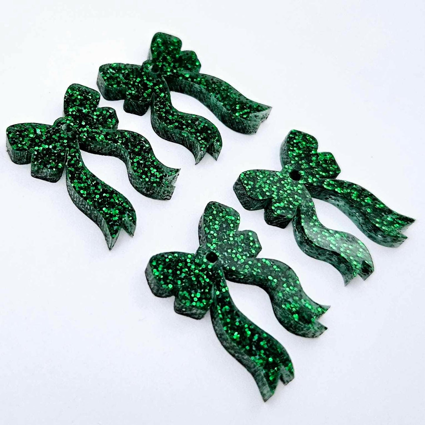 Two pairs of green glitter acrylic bow dangle earring blanks laying flat
