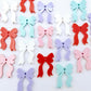 A selection of solid red, white, pastel pink, pastel purple and pastel aqua acrylic bow dangle earring blanks laying flat
