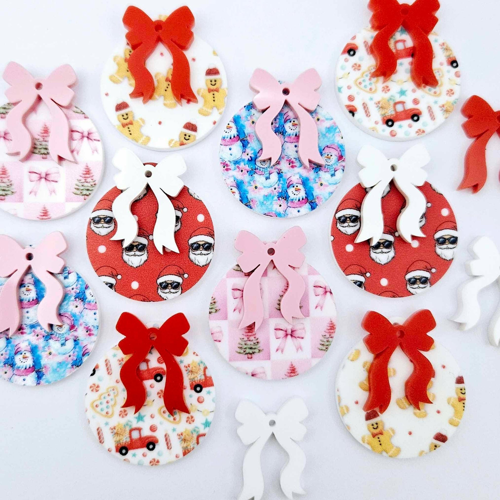 A selection of the five Fun Christmas UV printed bauble dangle earring blank designs with their coordinating bows laying flat.