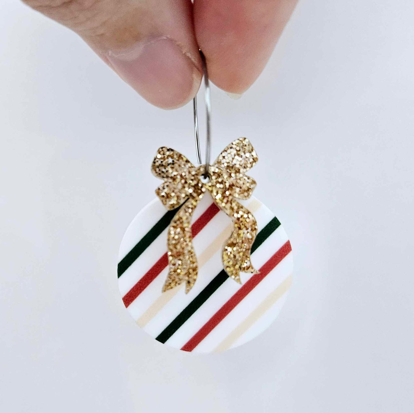 One rose gold glitter acrylic bow shown paired with a UV printed bauble on a 20mm hoop