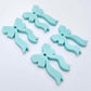 Two pairs of pastel aqua acrylic bow dangle earring blanks laying flat