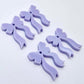 Two pairs of pastel purple acrylic bow dangle earring blanks laying flat