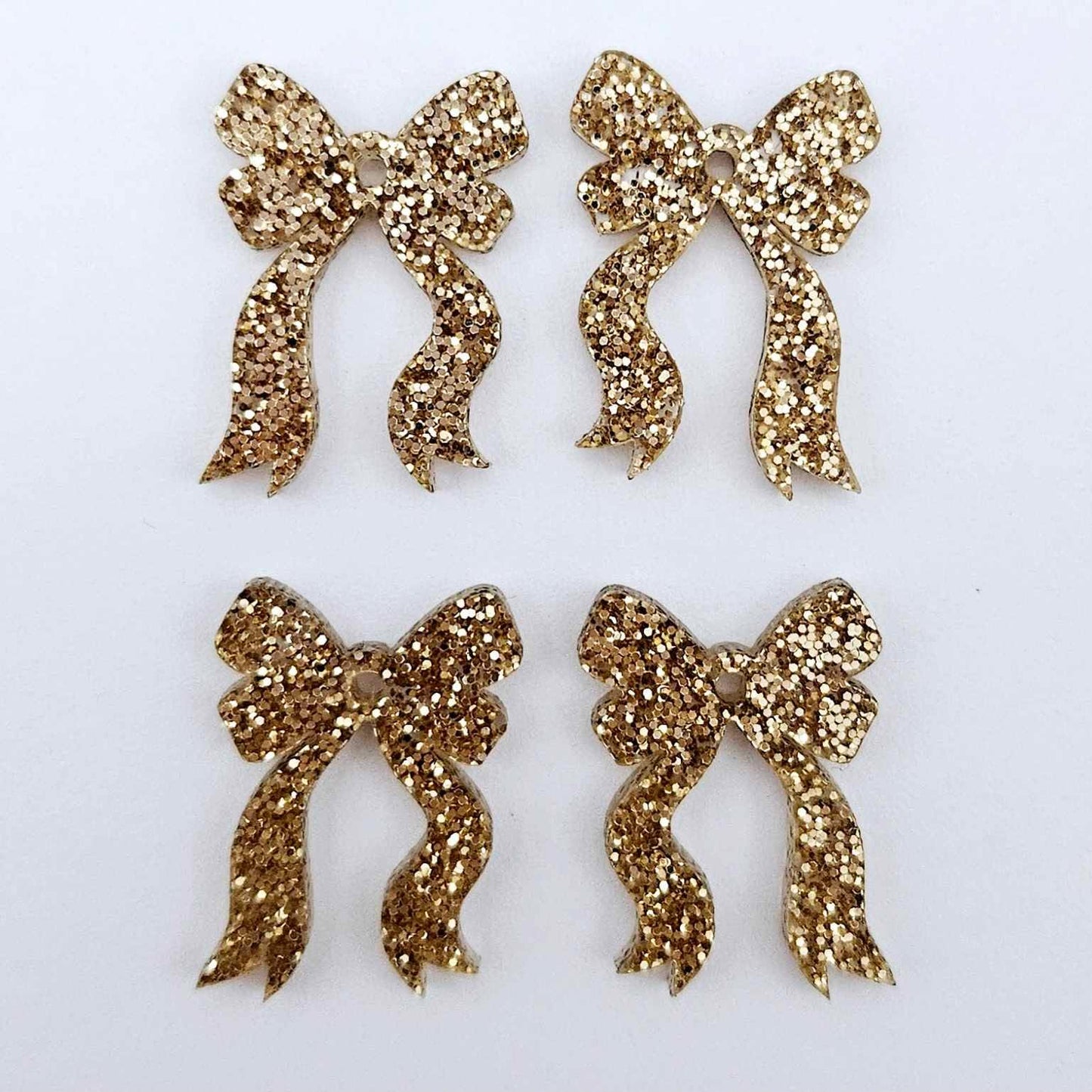 Two pairs of rose gold glitter bow dangle earring blanks laying flat