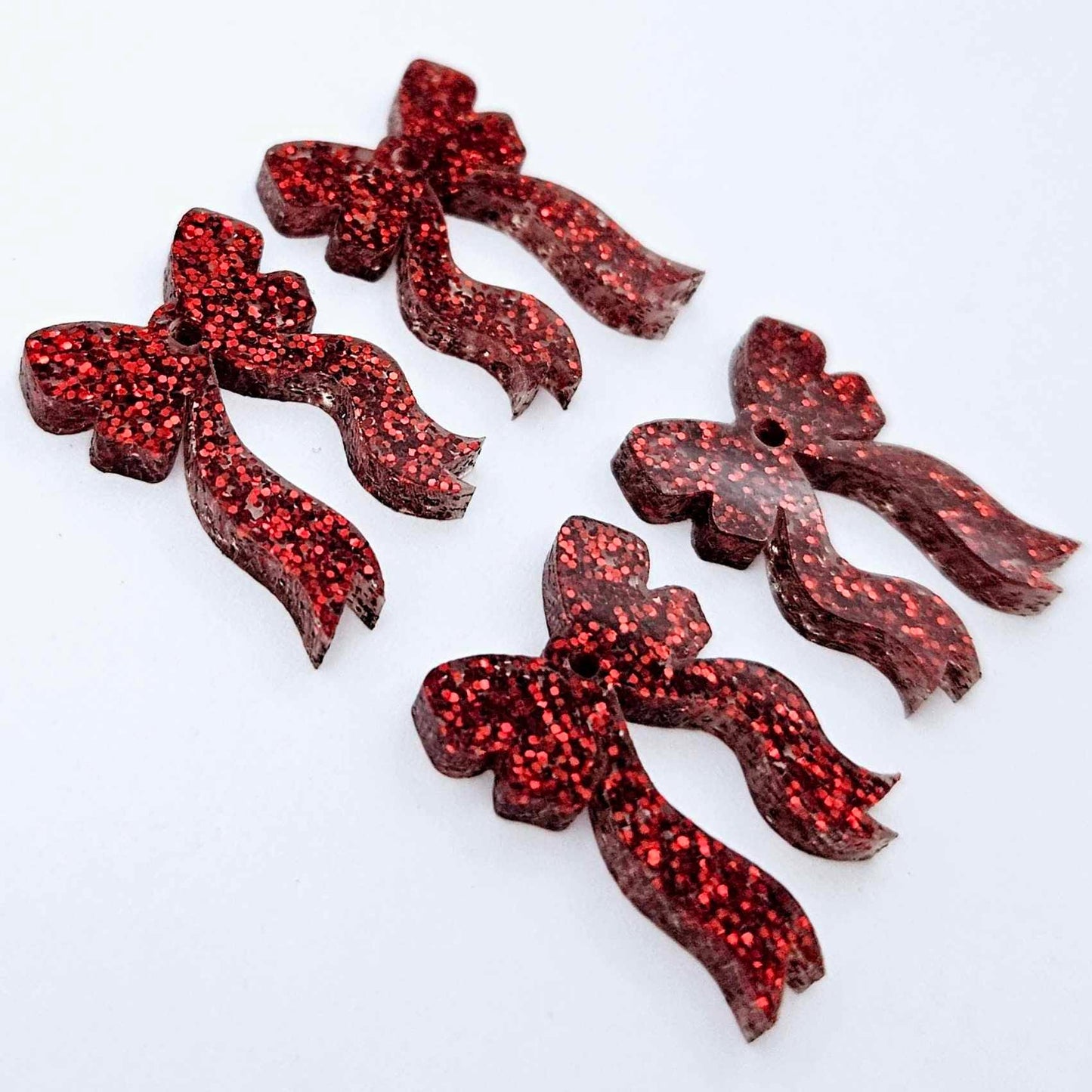 Two pairs of red glitter acrylic bow dangle earring blanks laying flat