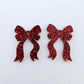 One pair of red glitter acrylic bow dangle earring blanks laying flat