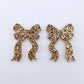 One pair of rose gold glitter bow dangle earring blanks laying flat