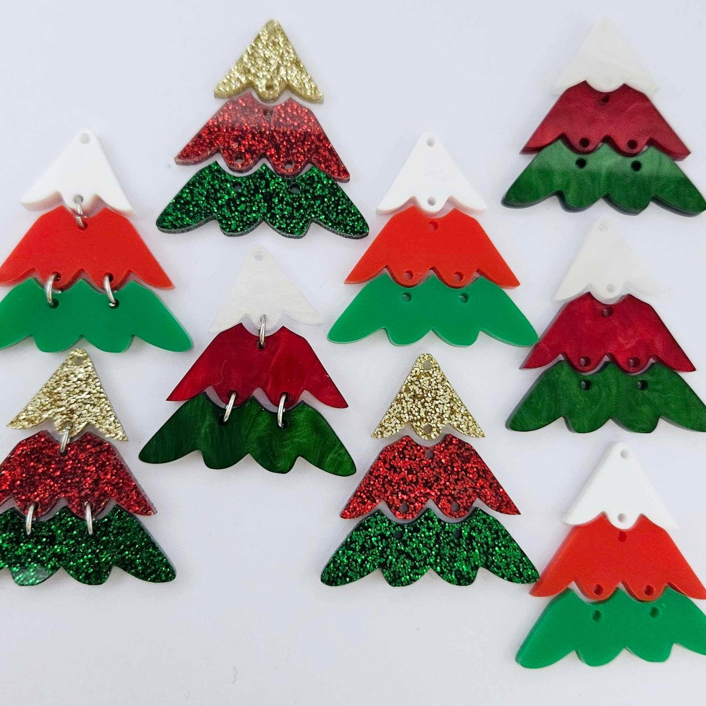 A mixture of the three traditional 40mm three piece Christmas Tree dangle blank designs laying flat on a white background