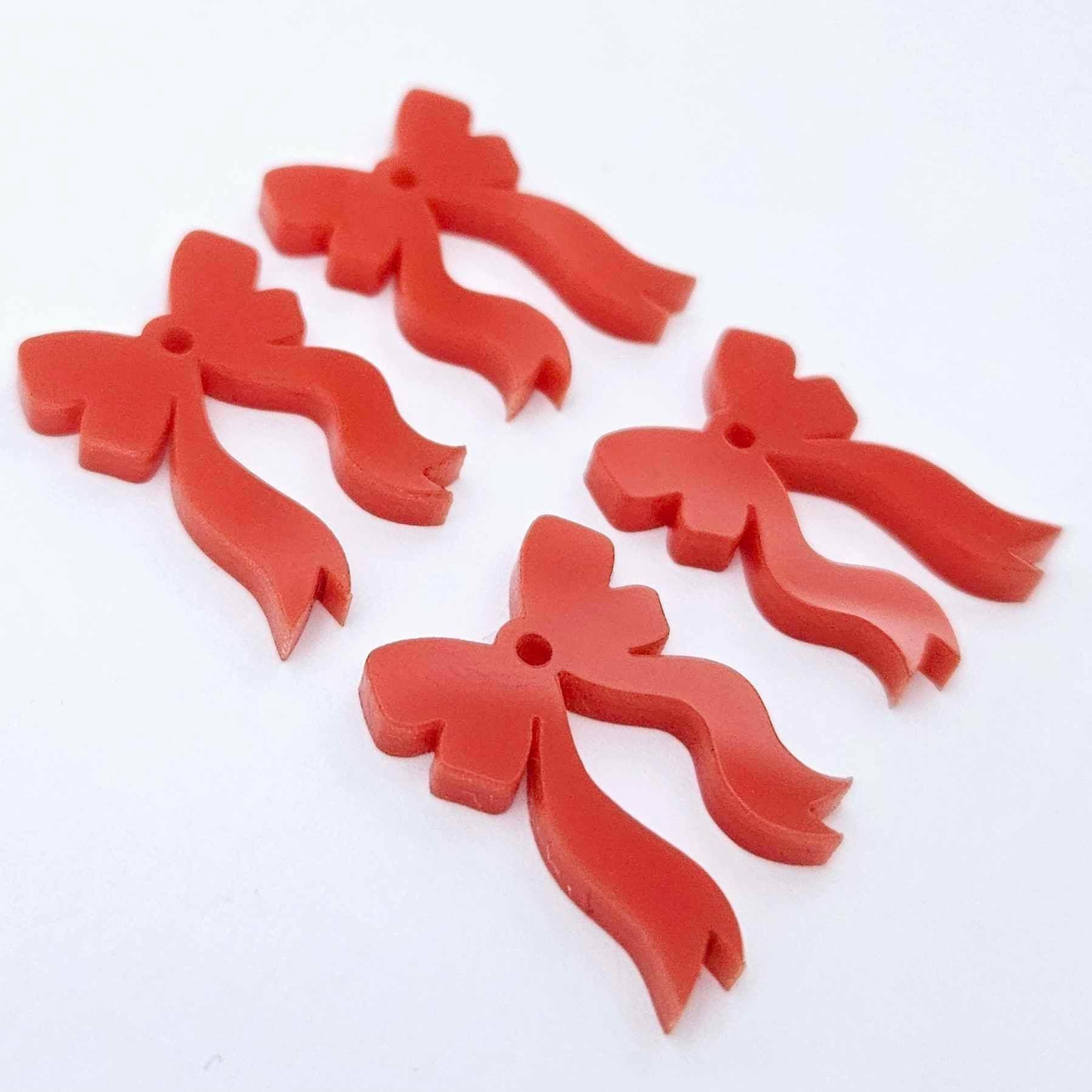 Two pairs of solid red acrylic bow dangle earring blanks laying flat