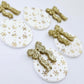 Two pairs of white Christmas Snowflake UV printed bauble dangle blanks with gold glitter bow connectors laying flat