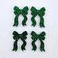 Two pairs of green glitter acrylic bow dangle earring blanks laying flat
